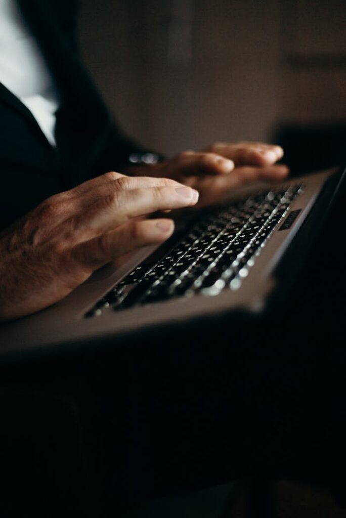 Close-up of hands typing on a laptop, focused on productivity and technology in a home office setting.